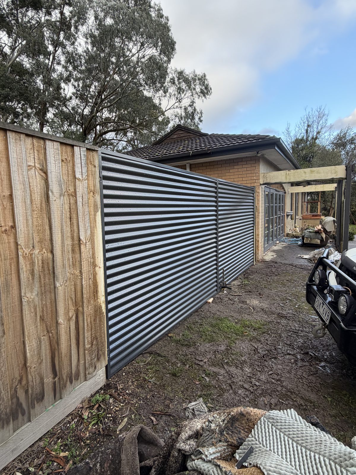 Corrugated steel slat gate beside a brick home